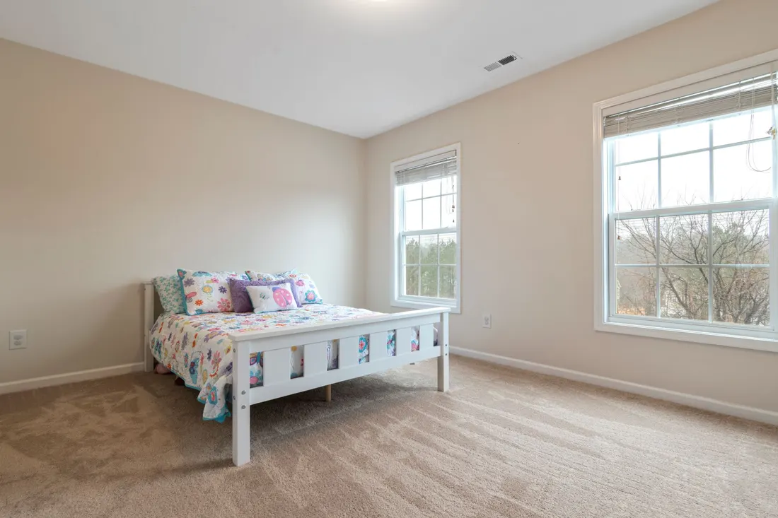 Quarto vazio com cama de solteiro, parede clara e janela